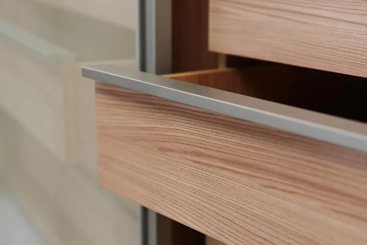 更衣室木皮抽屜櫃體近景，天然木紋紋理搭配鋁框把手，展現義大利衣櫃設計的溫潤質感