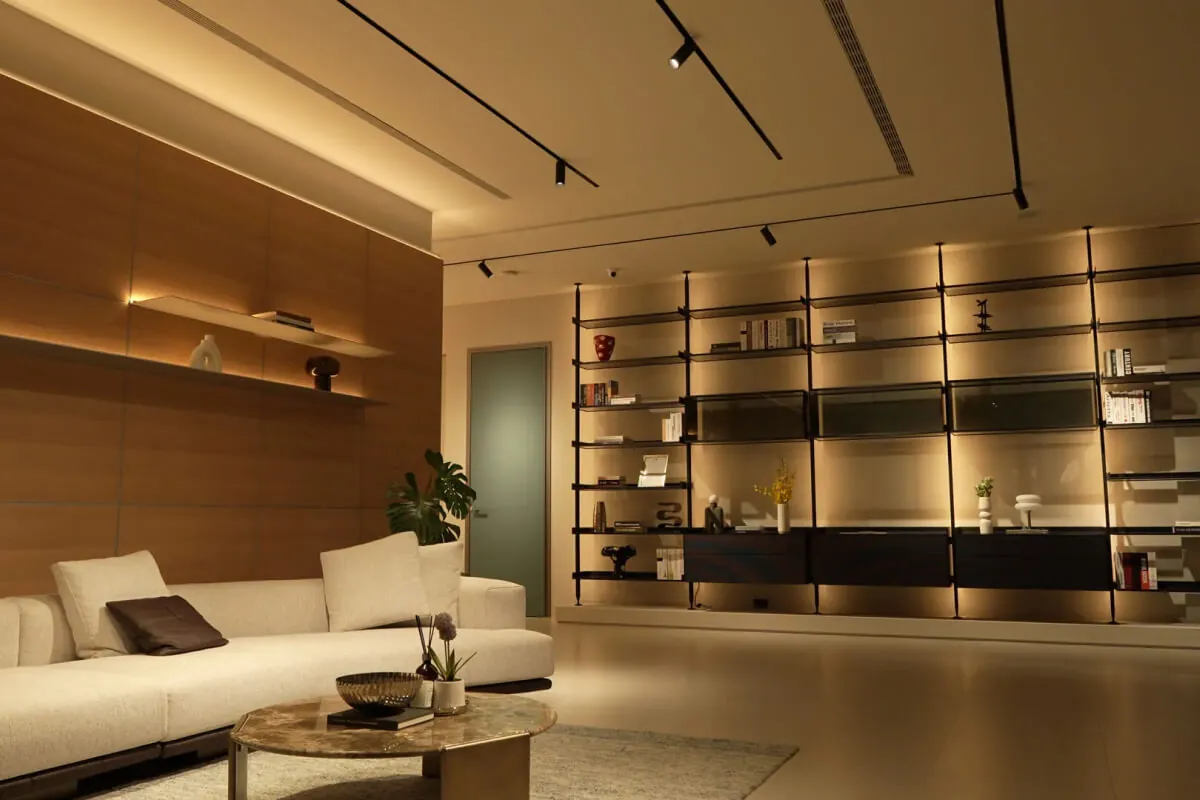 義大利家具客廳實景，布面沙發搭配大理石茶几與義式鋁框開放書架系統，展現進口家具的材質深度與建築感空間整合