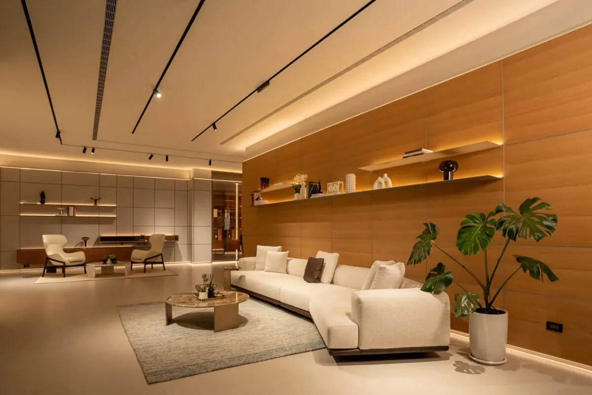 Loma Casa 台中義大利家具展示空間全景，木皮主牆搭配布面沙發、大理石茶几與書架收納牆，提供高端家具選購的完整空間參考